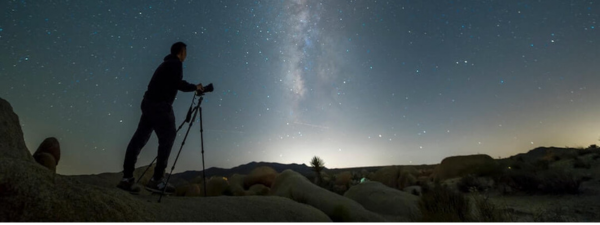 Stjernehimmel En mand med en stjernekikkert der kigger på stjerne en mørk nat